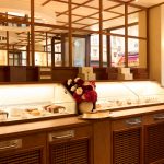 Interno di pasticceria a Parigi con vetrine refrigerate CIAM modello 6040 personalizzate, piano perimetrale su misura, vassoi in Corian Bone e dettagli verniciati RAL 8003 e RAL 9001